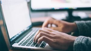 Person using a laptop at a desk, illustrating website search referrals and AI search traffic analysis